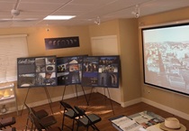 The presentation room with exhibit posters and showing a PowerPoint presentation. For more information; call (619) 688-6670 or email CT.Public.Information.D11@dot.ca.gov