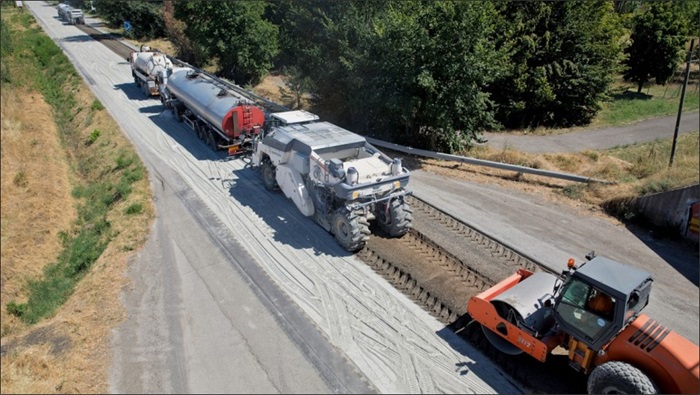 aerial view of a full depth reclamation train performing work on pavement during day construction 