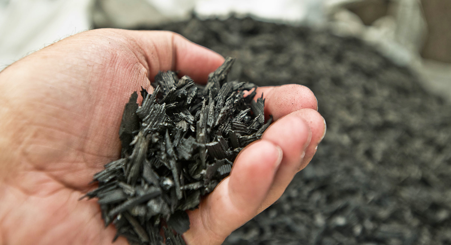 Photo: close-up view of a hand holding small bits of shredded rubber to be used for transportation projects