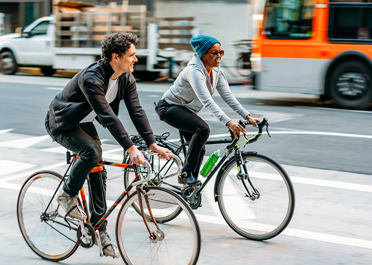 Photo of two bicyclists in downtown Los Angeles with a city bus in the background.