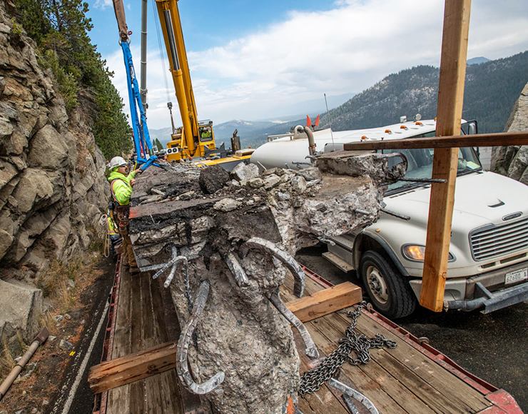 Workers load parts of old bridge onto a truck to be hauled away.