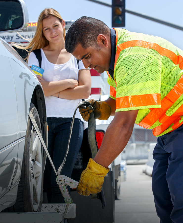 A Freeway Service Patrol worker assists woman on the highway.