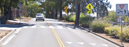 Image of a car approaching a crosswalk enhancements that includes a high-visibility crosswalk markings and advance stop/yield/pedestrian crossing markings and signs